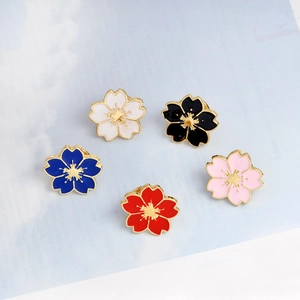 Detailed close-up of cherry blossom enamel pins in white, pink, blue, red, and black