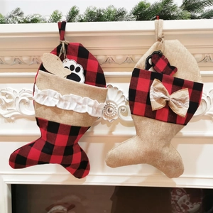 Detail von fischförmigen Weihnachtsstrümpfen aus rotem Karo und Jute am weißen Kamin