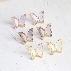 Macro detail of glass butterfly stud earrings in purple and clear tones on stone