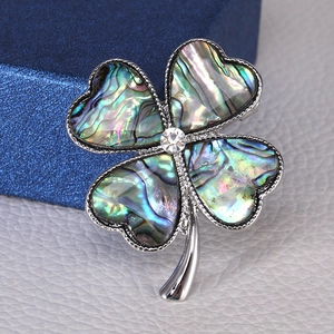 Macro view of clover brooch with colorful abalone shell and crystal center detail