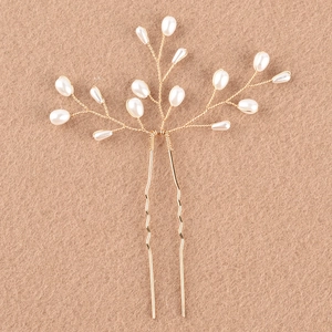 Détail d'un pic à cheveux artisanal en fil doré orné d'élégantes perles blanches