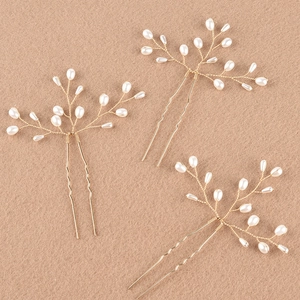 Détail d'épingles à cheveux de mariée en or fait main avec perles blanches sur fond texturé