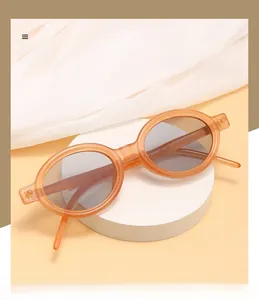 Detailed macro shot of vintage oval sunglasses with amber frames and dark grey lenses