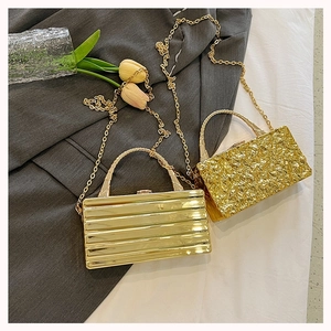 Detail of luxury acrylic box bags with gold stripe and foil texture and metal chains
