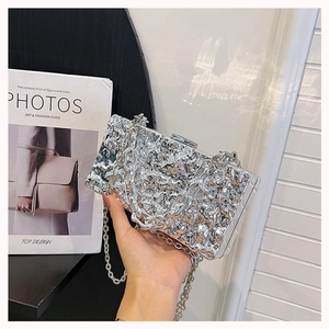 Close-up of silver metallic evening bag with liquid ripple texture and sleek chain strap