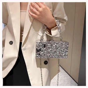 Detail view of silver acrylic evening bag with hammer texture and elegant metal chain strap