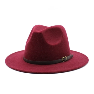 Detail of burgundy wool fedora hat featuring a brown leather band and gold metal buckle