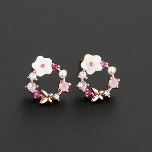 Floral hoop earrings with pearl shells and butterfly detail on a black background