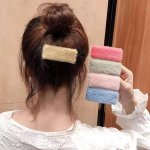 Detail view of five colors of fuzzy plush rectangular hair clips in soft pastel shades