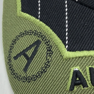 Close-up of olive green cotton twill fabric with precision black embroidered letter A