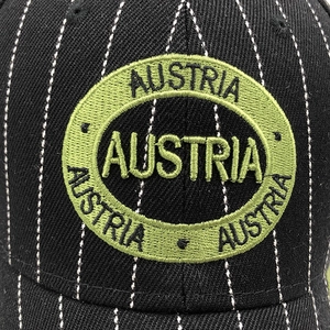 Close-up of Austria embroidery patch on striped cotton baseball cap front detail