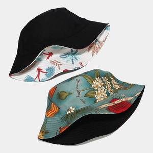 Reversible bucket hat with black solid side and teal botanical print with Spanish text