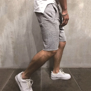 Side view of grey knit sports shorts for men featuring raw hems and side pockets