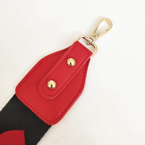 Détail de la bandoulière en jacquard rouge avec fermoirs dorés et finitions cuir