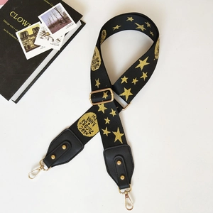 Detail view of wide adjustable nylon bag strap with gold star patterns and metal hooks