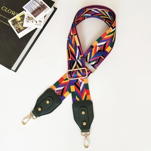 Close-up of ethnic geometric woven strap with green leather ends and gold metal buckles