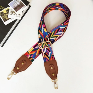 Close-up of adjustable geometric pattern shoulder strap with gold metal hooks and leather tips