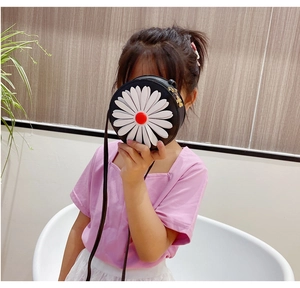 Detailed view of kids daisy crossbody bag with white petals and red center on black leather