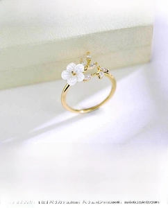 Detail view of champagne gold floral ring with mother of pearl petals and zircon accents