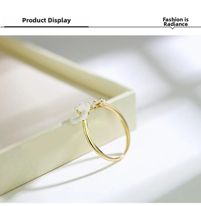Close-up of a gold flower ring featuring a white petal design and sparkling accents