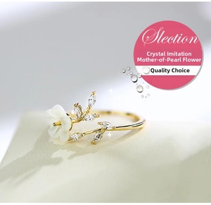 Detailed close-up of a gold ring with a white shell flower and crystal leaves