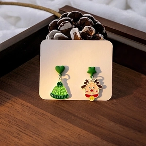 Close-up of Christmas reindeer and green knitted hat earrings on wooden tray