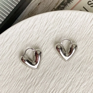 Primer plano de pendientes de aro con forma de corazón hueco de plata pulida