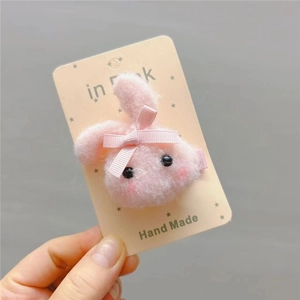 Close-up of pink plush bunny hair clip with bow on card, high-quality handmade hair accessory