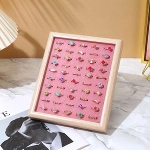 Walnut wood jewelry tray with pink velvet lining displaying assorted gemstone rings