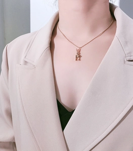 Close-up of golden movable rabbit pendant necklace on model with pink blazer