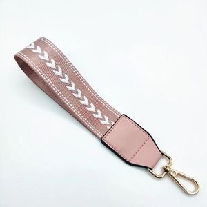 Close-up of pink woven nylon wrist strap with white patterns and gold lobster clasp