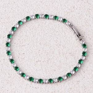 Detail of silver tennis bracelet with alternating green and white cubic zirconia stones
