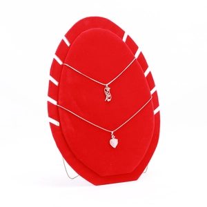 Detail of pink crystal heart and letter pendants on a red velvet jewelry display stand