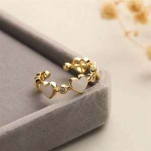 Macro detail of gold open ring featuring white heart inlay and micro cubic zirconia