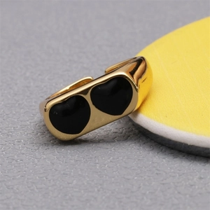 Detail of 18K gold-plated ring showing two black enamel heart motifs with a glossy finish