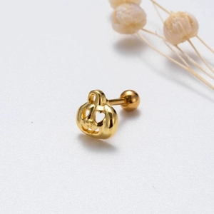 Macro shot of gold stainless steel pumpkin stud earring with hollow Jack-o'-lantern face
