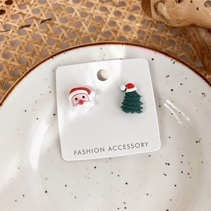 Detailed view of asymmetric Santa Claus and Christmas tree stud earrings on white card