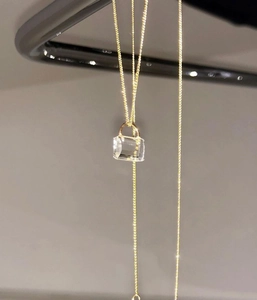 Detail shot of the golden handbag-shaped pendant with high-clarity crystal and metal chain