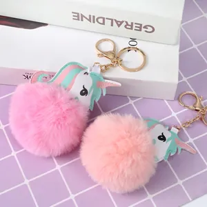 Charming unicorn plush ball keychain with golden ring on purple checkered background