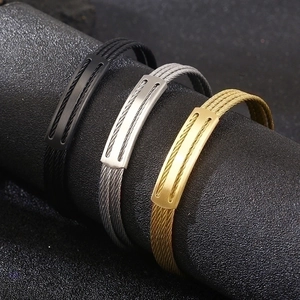 Detailed view of three-color stainless steel wire cable bracelets on a black display stand