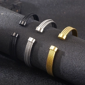 Macro detail of multi-layered stainless steel cable bracelets in gold, silver and black