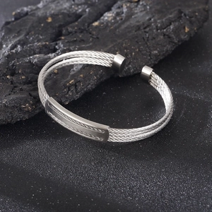 Detail view of double-stranded steel wire braid cuff bracelet on dark rock background