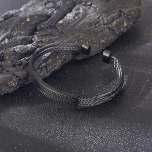 Detail of black woven stainless steel wire cuff bracelet with textured central connector