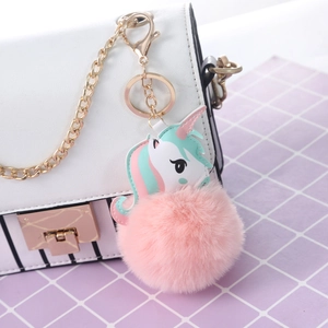 Close-up of pink faux rabbit fur unicorn keychain with gold metal clasp on a bag