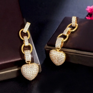 Luxurious gold heart pendant earrings with micro-paved zircons on a jewelry box