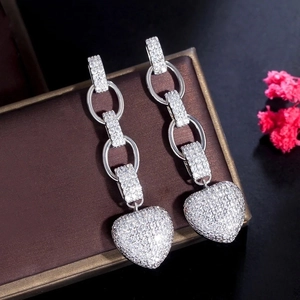 Macro shot of silver heart drop earrings with white crystals on a jewelry box