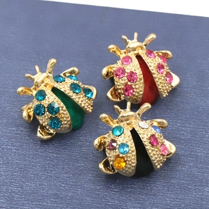 Fashionable ladybug brooches with colorful rhinestones on a navy textured background