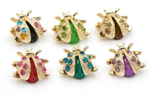 Flat lay detail of alloy ladybug brooches with colorful rhinestones and gold metal base