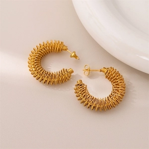 Golden spiral hoop earrings with hollow metal twist design on a textured background