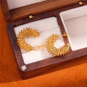 Golden spiral spring hoop earrings in geometric twisted style on jewelry box